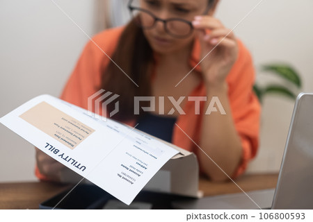 Irritated young woman looks at utility bill worried about troubles with mortgage payment to bank lady haves serious problems with debt at table with laptop at home 106800593