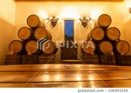 Interior of wine restaurant with rustic wooden table and oak barrels in the background. Interior of wine restaurant with rustic wooden table and oak barrels in the background. 106801036