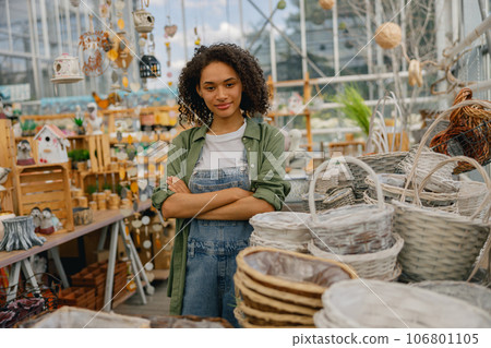 Smiling female garden shop seller standing with crossed hands on flower store background 106801105