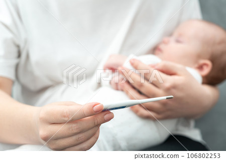 Concerned mother checks for fever in her newborn. Concept of infant health vigilance Concerned mother checks for fever in her newborn. Concept of infant health vigilance 106802253