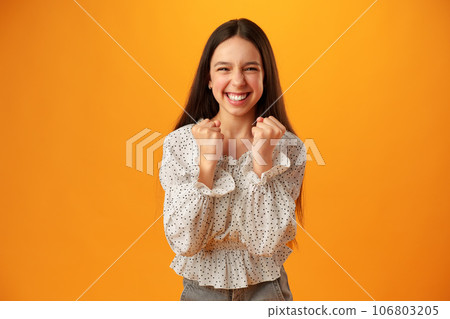 Portrait of a joyful happy teenage girl celebrating success on yellow background Portrait of a joyful happy teenage girl celebrating success on yellow background 106803205