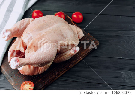 Raw whole chicken carcass on wooden cutting board 106803372