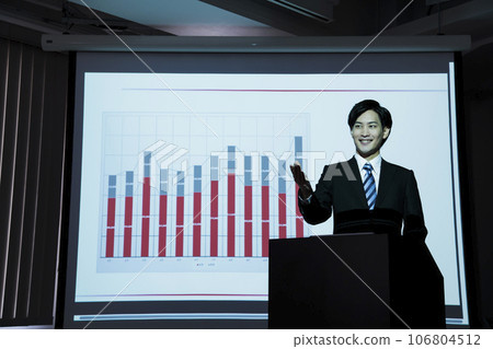 A young businessman giving a presentation using a projector at a meeting 106804512
