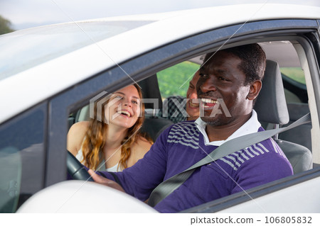 Laughing african american man driving car with cheerful passengers Laughing african american man driving car with cheerful passengers 106805832