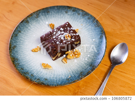 Slice of chocolate biscuit cake with powdered sugar and walnuts Slice of chocolate biscuit cake with powdered sugar and walnuts 106805872