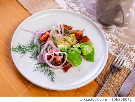 Vegetable salad of tomatoes, avocado and onions is decorated with sprig of dill, sprinkled with herbs Vegetable salad of tomatoes, avocado and onions is decorated with sprig of dill, sprinkled with herbs 106806072