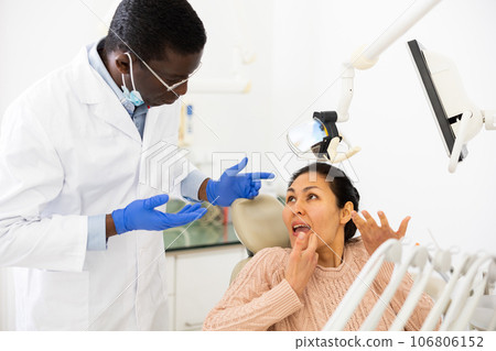 Dissatisfied woman talking to confused dentist after dental treatment 106806152