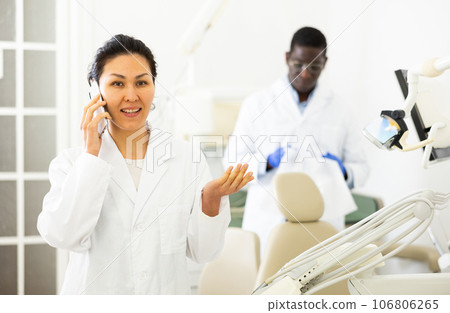 Portrait of female dentist talking on phone in clinic Portrait of female dentist talking on phone in clinic 106806265