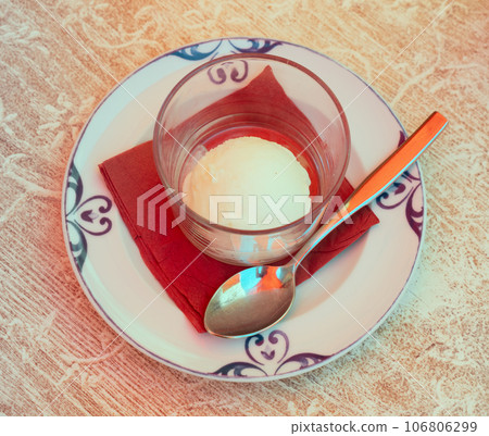 On napkin-covered plate is glass with a refreshing dessert - lemon sorbet. 106806299