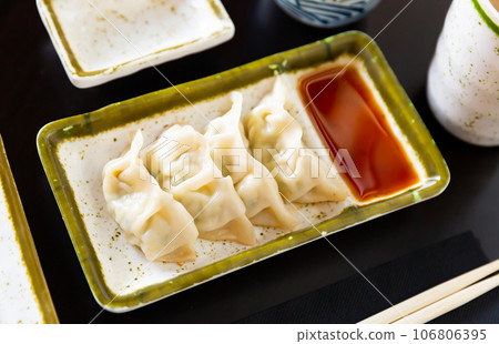 Japanese boiled gyoza dumplings served with tare sauce 106806395