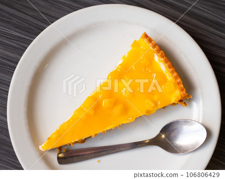 Piece of airy and delicate cheesecake pie, top layer of which decorated with small pineapple cubes 106806429