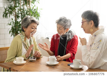 Senior friends having tea at a cafe Senior women looking at smartphones 106807776
