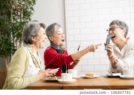 Senior friends having tea at a cafe Senior women looking at smartphones 106807781