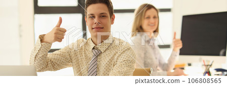 Two managers are sitting at their desks in office and showing thumbs up gesture. Two managers are sitting at their desks in office and showing thumbs up gesture. 106808565