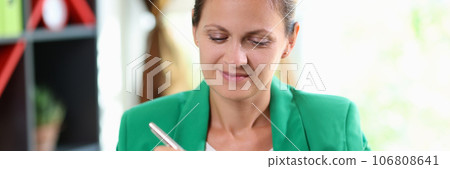 Satisfied business woman smiling and writing notes in her notepad in the office. 106808641