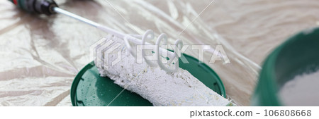 Paint mixer, roller brush and bucket with white paint on covered floor. Paint mixer, roller brush and bucket with white paint on covered floor. 106808668