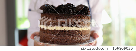 Dietologist holds whole chocolate cake and warns against overeating. Dietologist holds whole chocolate cake and warns against overeating. 106809039