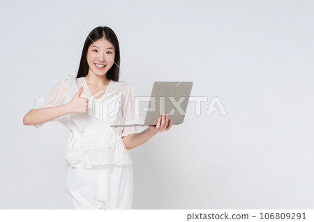 Young asian woman holding a laptop and showing thumbs up isolated on white background. Young asian woman holding a laptop and showing thumbs up isolated on white background. 106809291