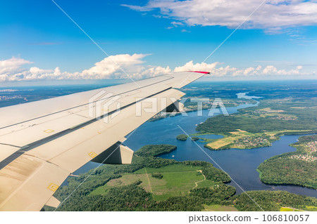 View of airplane wing, blue skies and green land during landing. Airplane window view. 106810057