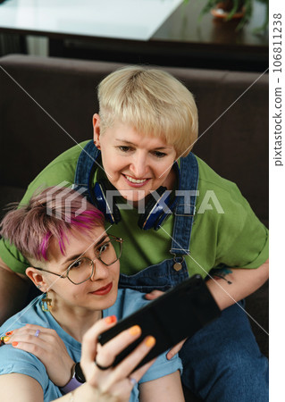 Adult mother and daughter take a joint selfie on a smartphone at home Adult mother and daughter take a joint selfie on a smartphone at home 106811238
