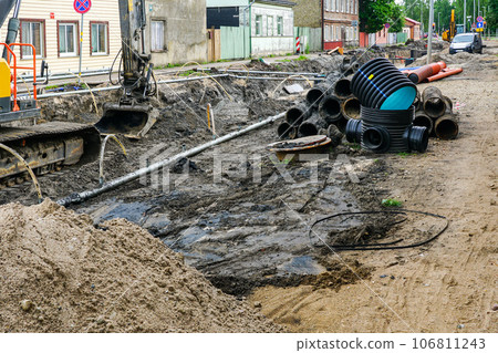 Street reconstruction view, old and new underground pipes next to a deep wide trench 106811243