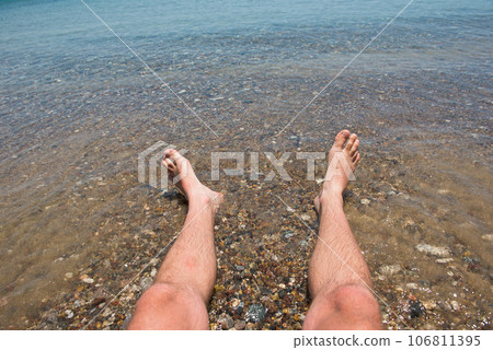 Sea waves washing man's feet 106811395