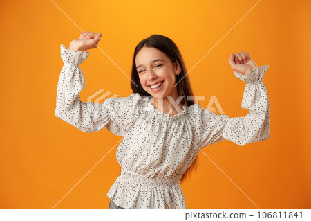 Portrait of a joyful happy teenage girl celebrating success on yellow background 106811841