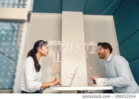 Two diverse business colleagues working together on project sitting in modern meeting room 106812054