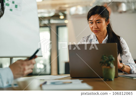 Two diverse business colleagues working together on project sitting in modern meeting room 106812065