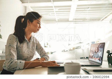 Businesswoman during online video conference with colleague while sitting in office 106812094