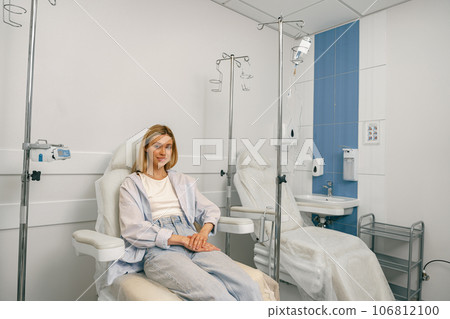 Smiling woman sitting in armchair while waiting for IV infusion during treatment in hospital Smiling woman sitting in armchair while waiting for IV infusion during treatment in hospital 106812100