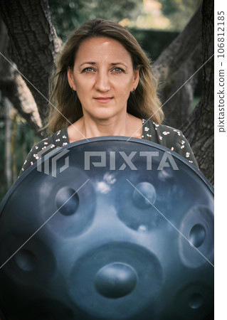 Portrait of a woman with a handpan her hands 106812185