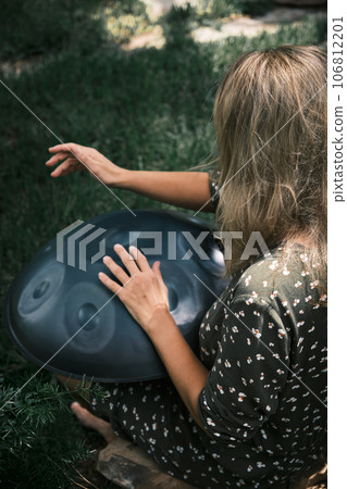 a woman plays on handpan or hang a woman plays on handpan or hang 106812201