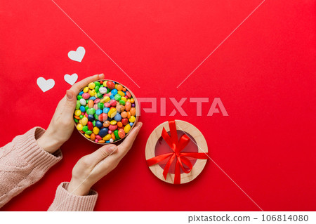 Female hands with delicious candies in box on color background 106814080