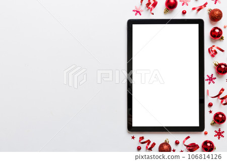 Christmas online shopping from home tablet pc with blank white display top view. Tablet with copy space on colored background with Christmas decorations balls,. Winter holidays sales background Christmas online shopping from home tablet pc with blank white display top view. Tablet with copy space on colored background with Christmas decorations balls,. Winter holidays sales background 106814126