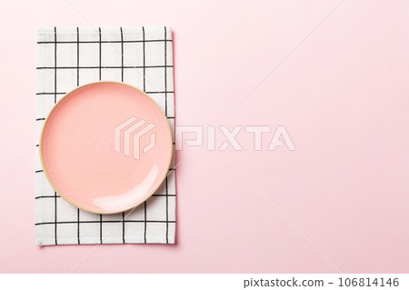 Top view on colored background empty round pink plate on tablecloth for food. Empty dish on napkin with space for your design Top view on colored background empty round pink plate on tablecloth for food. Empty dish on napkin with space for your design 106814146