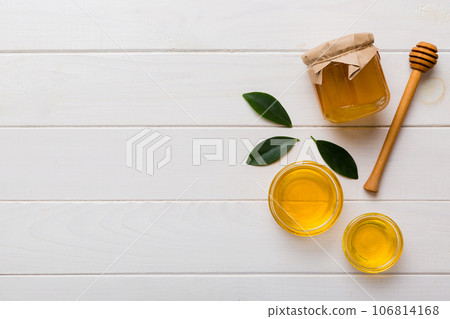 Honey jar with wooden honey dipper on white background top view with copy space. Delicious honey bottle Honey jar with wooden honey dipper on white background top view with copy space. Delicious honey bottle 106814168