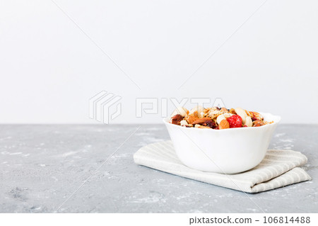 Cooking a wholesome breakfast. Granola with Various dried fruits and nuts in a bowl. The concept of a healthy dessert. Flat lay, top view with copy space Cooking a wholesome breakfast. Granola with Various dried fruits and nuts in a bowl. The concept of a healthy dessert. Flat lay, top view with copy space 106814488