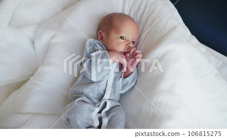newborn. baby newborn a close-up lies looking at the camera in lifestyle the hospital maternity hospital. happy family baby dream concept. cute newborn baby in gray clothes newborn. baby newborn a close-up lies looking at the camera in lifestyle the hospital maternity hospital. happy family baby dream concept. cute newborn baby in gray clothes 106815275
