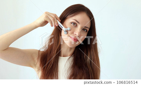 A beautiful woman gives a facial massage with a silver facial massager to relieve facial swelling A beautiful woman gives a facial massage with a silver facial massager to relieve facial swelling 106816514