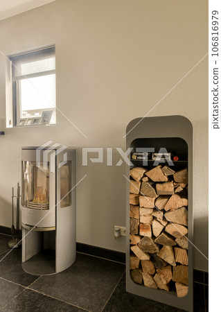 a fire place in the corner of a room with wood stacked up on it's sides and an open door a fire place in the corner of a room with wood stacked up on it's sides and an open door 106816979
