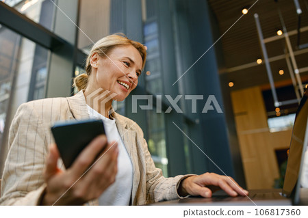 Close up of female entrepreneur use phone while working on laptop in modern office background Close up of female entrepreneur use phone while working on laptop in modern office background 106817360