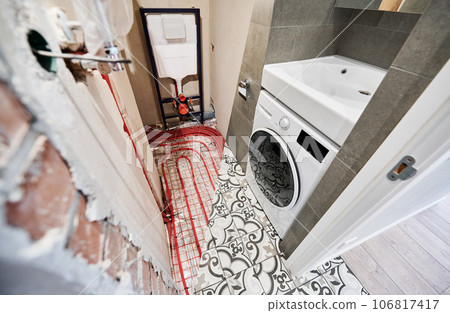 Comparison of washroom lavatory before and after renovation. Old apartment restroom with underfloor heating pipes and new renovated toilet room with washing machine. 106817417