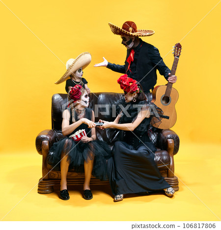 Halloween Family. Father, mother and children in halloween skeleton spooky makeup arguing what they want watch on TV against yellow background. 106817806
