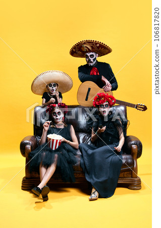 Halloween Family. Father playing on guitar, mother and children in halloween skeleton spooky makeup watching films with pop corn. 106817820