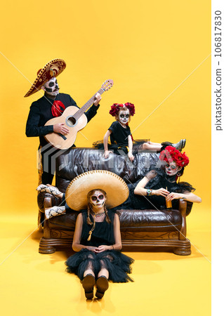 Halloween Family. Happy father, mother and children girls in halloween mexico costume and makeup. Crazy skeleton faces on yellow studio background 106817830