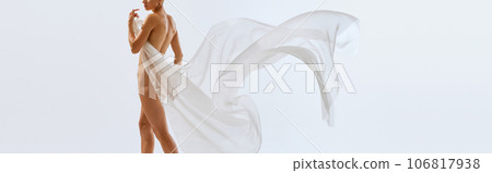 banner. poster. Cropped portrait of young sensual naked woman with white floating tissue covering her body, hips, buttocks. 106817938