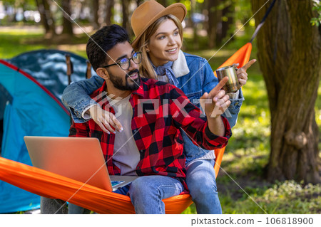 Young freelancer working on laptop in the forest, with his girlfriend next to him Young freelancer working on laptop in the forest, with his girlfriend next to him 106818900