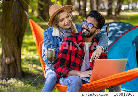 Young freelancer working on laptop in the forest, with his girlfriend next to him Young freelancer working on laptop in the forest, with his girlfriend next to him 106818903