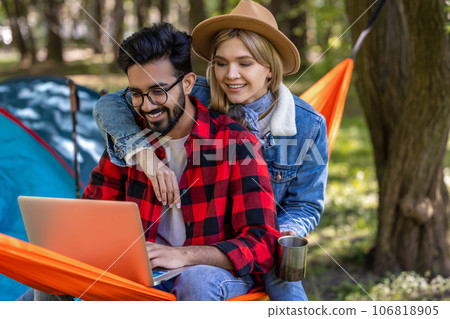 Young freelancer working on laptop in the forest, wit his girlfriend next to him Young freelancer working on laptop in the forest, wit his girlfriend next to him 106818905